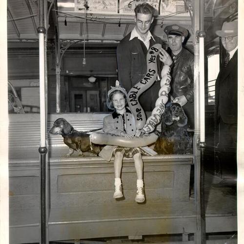 [Barbara Wiley and her two dogs, Hans and Christopher, riding a cable car on their way to a "Pooch Parade"]
