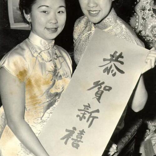 [Carolyn Lim and Katherine Chan holding a card that reads "Happy New Year"]
