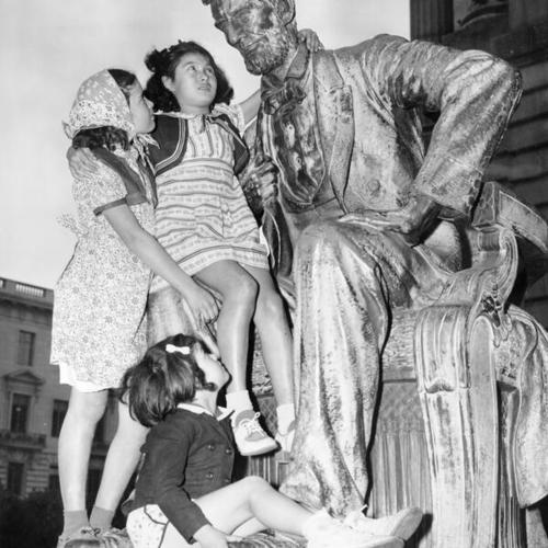 [Young girls sit on Abraham Lincoln statue]