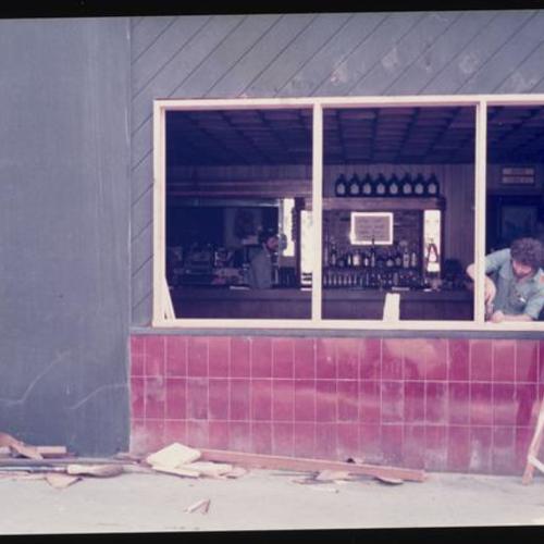 Exterior view of bartender John Swindle installing new window
