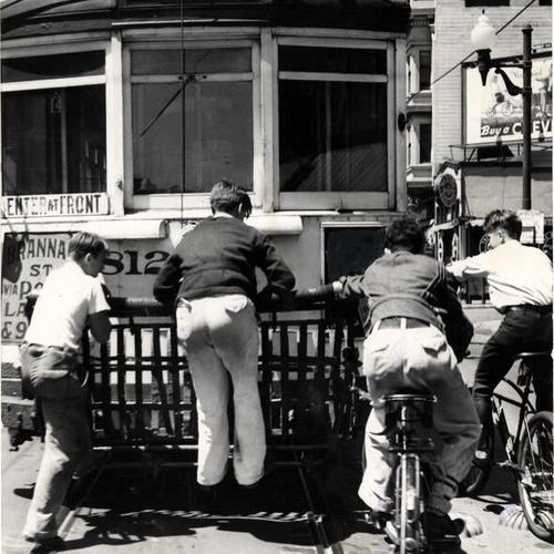 [Children riding on the rear bumper of a streetcar]