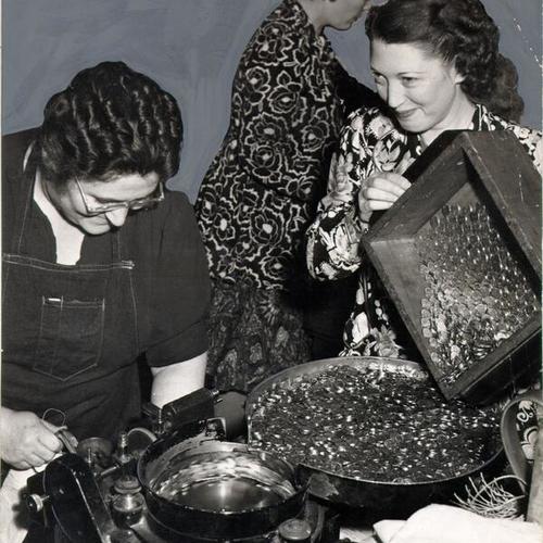 [Dorothea Huering and Lucille Flores pouring pennies into a counting machine at the U. S. Mint in San Francisco]