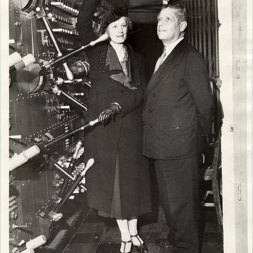[Mrs. Norman H. Sloane and Max Reinhardt standing next to the electrical switchboard at the War Memorial Opera House]