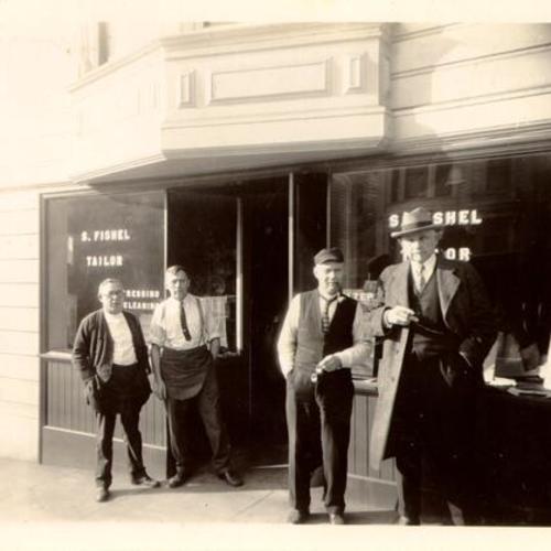 [Four men standing in front of S. Fishel Tailor]