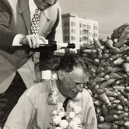 [John Brucato pouring a bottle of wine over the head of farmer Paul Holme at the Farmers' Market at Market and Duboce streets]