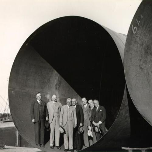 [Group of engineers and officials involved in the construction of the San Francisco-Oakland Bay Bridge posing inside a dredging well]