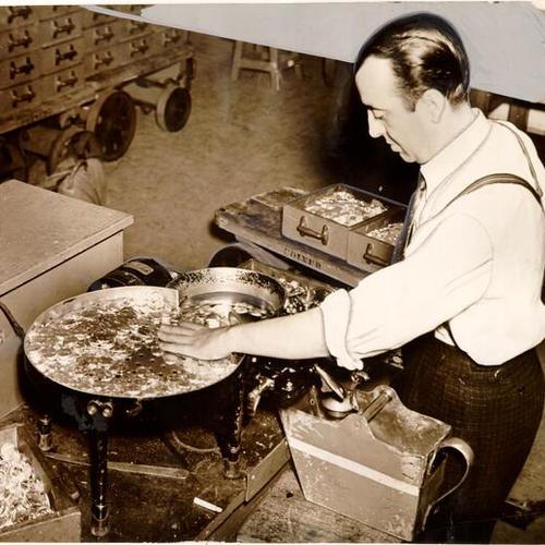 [Frank Amoroso putting coins through a counting machine at the U. S. Mint in San Francisco]