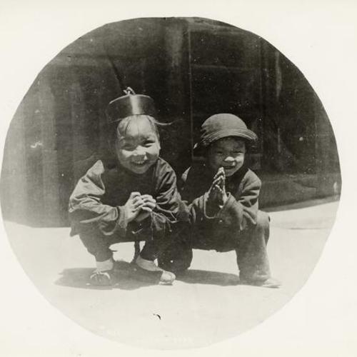 [Two young Chinese boys squatting]