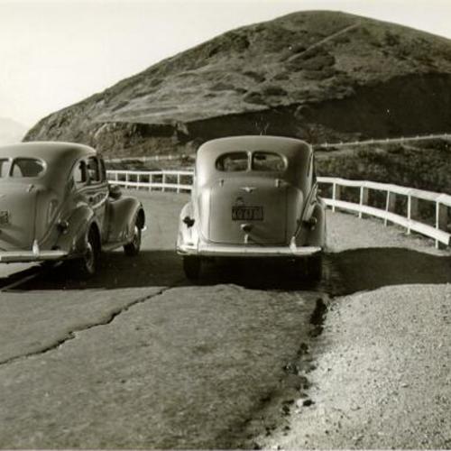 [Two cars on a Twin Peaks road]