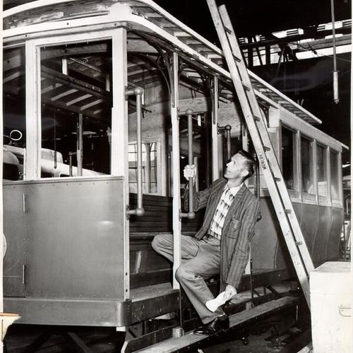 [Foreman Clyde Dietzen checking work on a cable car being reconstructed at Ocean and San Jose avenues]