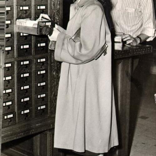 [Patron Mary June King looking up a book in the card catalog at the Main Library]