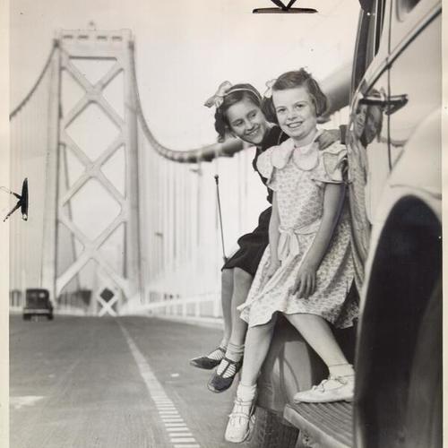 [Orphans, Dorothy and Anna, sitting on a car parked on the bridge during a preview visit of the San Francisco-Oakland Bay Bridge]