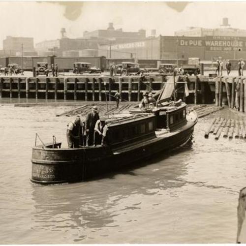 [Men dropping line in water from police patrol boat near Townsend and First Streets]