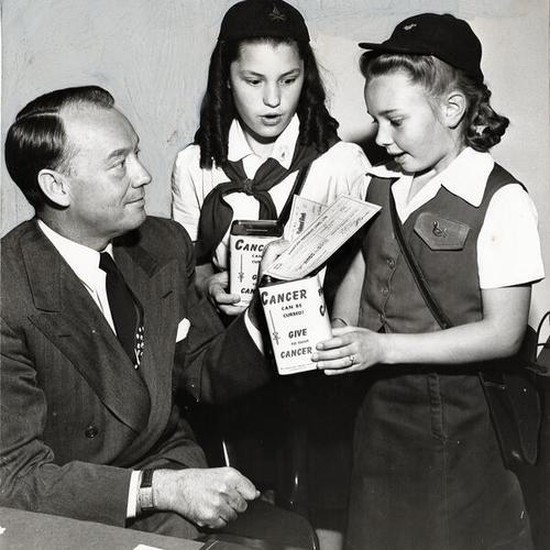 [Camp Fire Girls Derryl DeGuire and Nancy Nicholson accept a $500 check from George Killion, president of American President Lines]