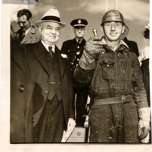 [Mayor Angelo Rossi and riveter Ed Stanley at a ceremony marking the driving of the last rivet during construction of the Golden Gate Bridge]