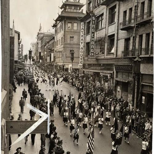 [Chinese school children marching with American and Chinese flags in a parade celebrating the founding of the Chinese republic]