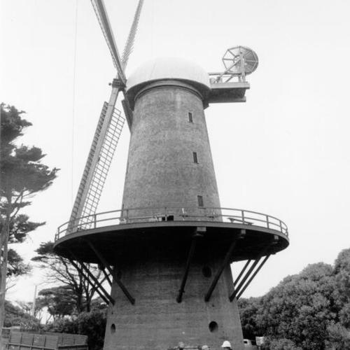 [Four unidentified people standing in front of windmill in Golden Gate Park]