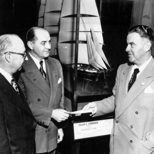 [James Sinclair, president of Luckenbach Steamship Co., center, presents a letter to Edward H. Harms, chairman of the Marine Museum Citizens Committee, promising to loan the fine model in the background to the museum]