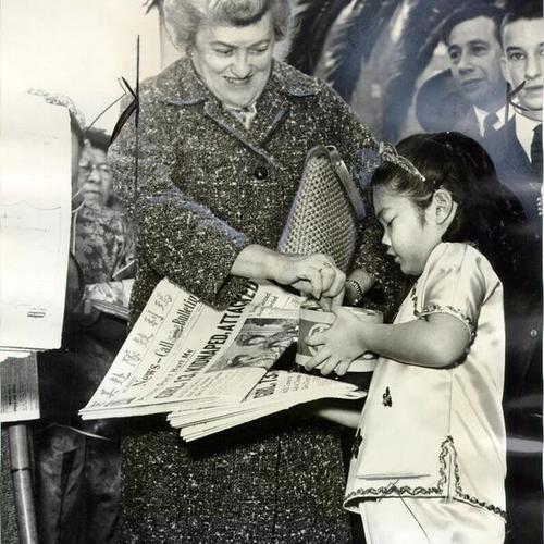 [Tia Chin, age 6, selling a copy of the News-Call Bulletin to Mrs. Gretel Weil as part of a fund drive to aid St. Mary's Chinese Girls Drum Corps]