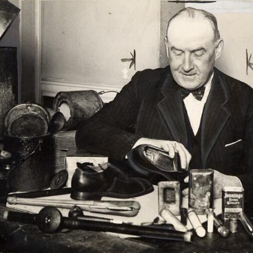 [Sergeant John Manion seated at his desk and examining a pair of shoes]