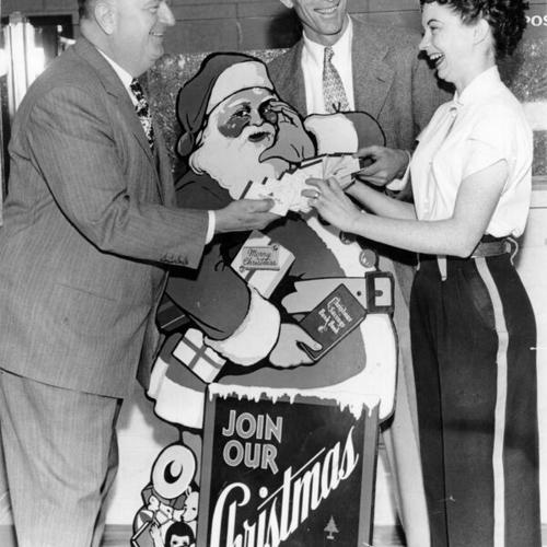 [J. C. Bonzani, manager of the 16th and Mission Street branch of Bank of America, with Mels Drive-In employees Raymond E. Walker and Dorothy Gregory]