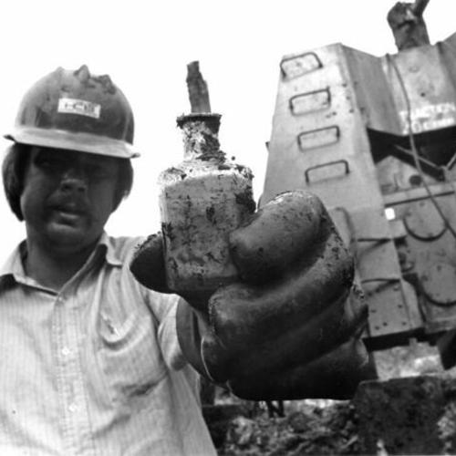 [Worker at construction site of Embarcadero Center holding a bottle dug up at the site]