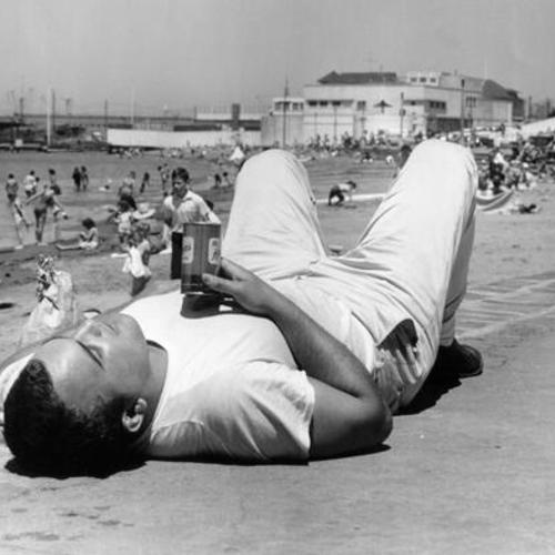 [Man lying on beach with beer can in Aquatic Park]