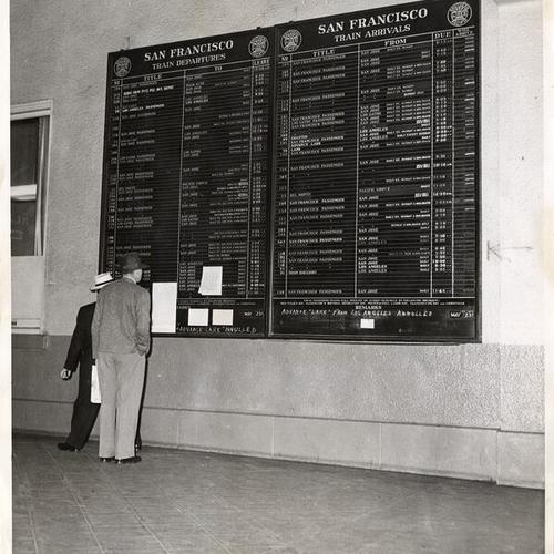 [Travelers reading train departure notices at the Southern Pacific Depot]