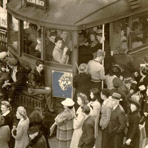 [People trying to board an overcrowded streetcar]