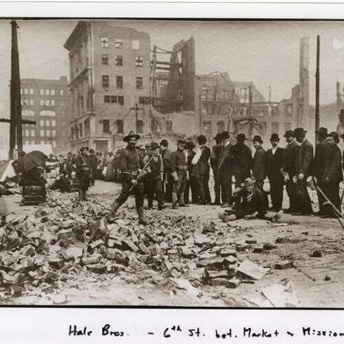 Soldiers watch over people in line at 6th Street between Market and Mission Streets with Hale Brothers Building in the background