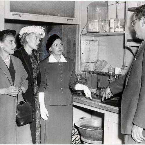 [Attorneys Anna Garlund, Lee Penland and Ruth Cessna discussing the condition of the crowded laboratory with Coroner Henry Turkel in Old Hall of Justice]