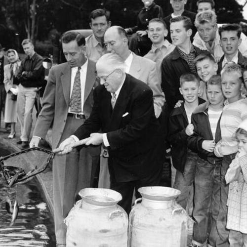 [Mayor Elmer E. Robinson releasing first fish to be stocked in Spreckels Lake in Golden Gate Park]
