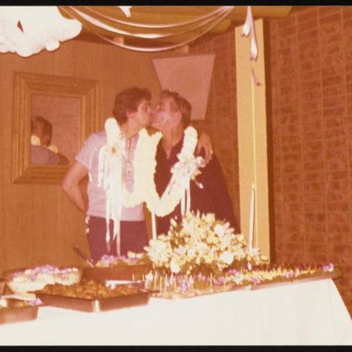 Jim and Ken kissing at table decorated for their wedding party