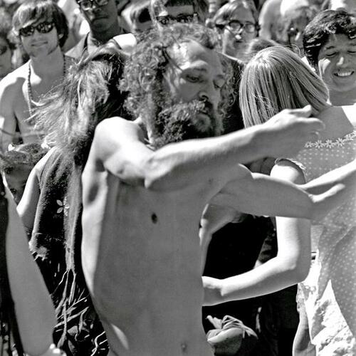 [Shirtless man free-form dancing amidst crowd at a summer music festival]