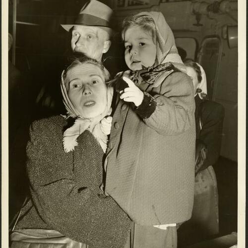 [Woman holding a child among the debarking passengers]