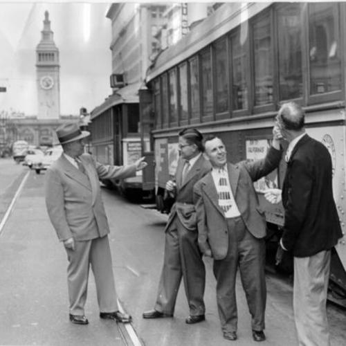 [Market Street merchants Ed Wickenhauser, Jack Moore, Jerry Gaff and Lester Secor standing next to parked streetcars on Market Street]
