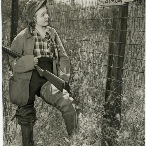 [Female hunter in front of "No hunting or trespassing" sign]