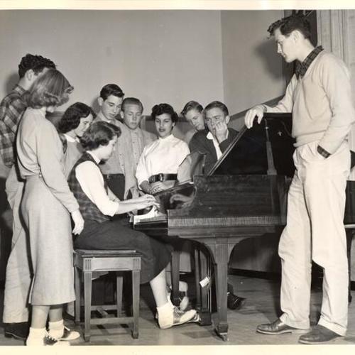 [Diane Braskamp and friends gathering around the piano of the new Park Presidio Branch of the Metropolitan Y.M.C.A.]