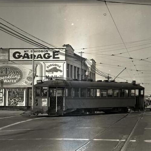 [Ocean avenue and Brighton street looking west at Muni "K" line car 155 turning in front of Mt. Davidson Garage]
