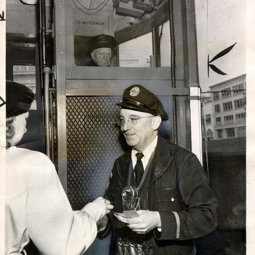 [Municipal Railway employee Joe Sullivan collecting fare from a passenger on a streetcar]