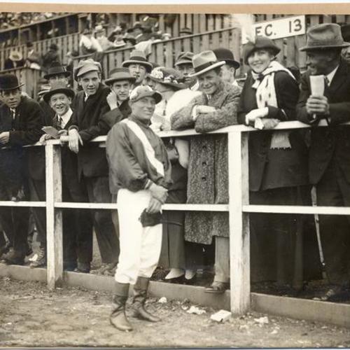 [Jockey T. T. Burns posing with spectators during horse race at the Panama-Pacific International Exposition]