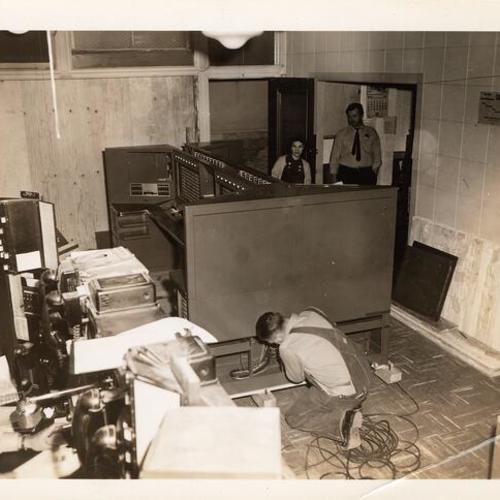 [Workmen anchoring new radio broadcasting console to floor in the Communications Room in Old Hall of Justice]