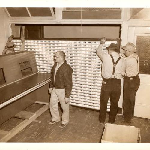 [Workmen adjusting a board in the Communications Room in Old Hall of Justice]