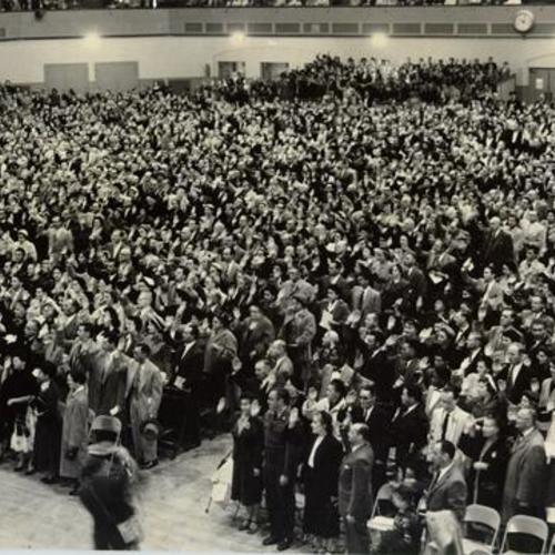 [Thousands of people taking an oath of citizenship at the San Francisco Civic Auditorium]