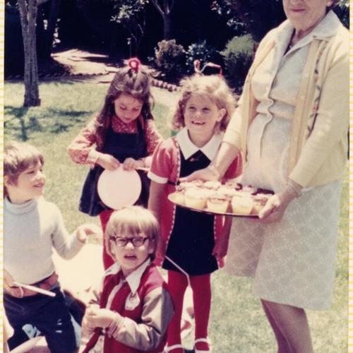 [Sylvia's birthday party with friends and her grandma holding cupcakes]