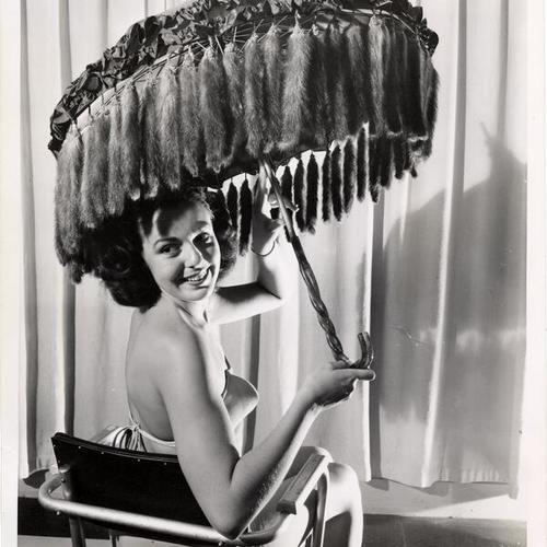 [Betty Cagney basks in the shade of a mink umbrella]