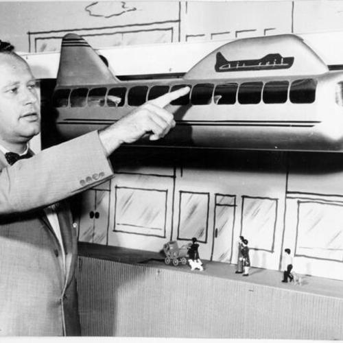 [Murel Goodell pointing to a scale model of a monorail car]