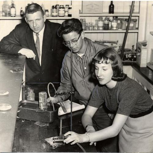 [Teacher Stewart Dimon watching students Jose Medrano and Diane Fabian conduct a chemistry experiment at Polytechnic High School]