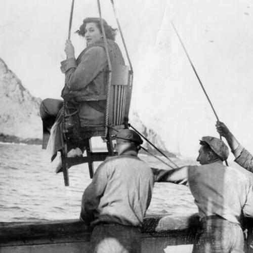 [Reporter Caroline Clifton being hoisted up on an improvised "bosun's chair"]