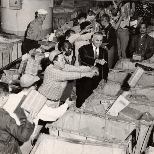 [Postmaster John Fixa standing amid clerks who are sorting the outgoing mail in the Rincon Annex Post office]